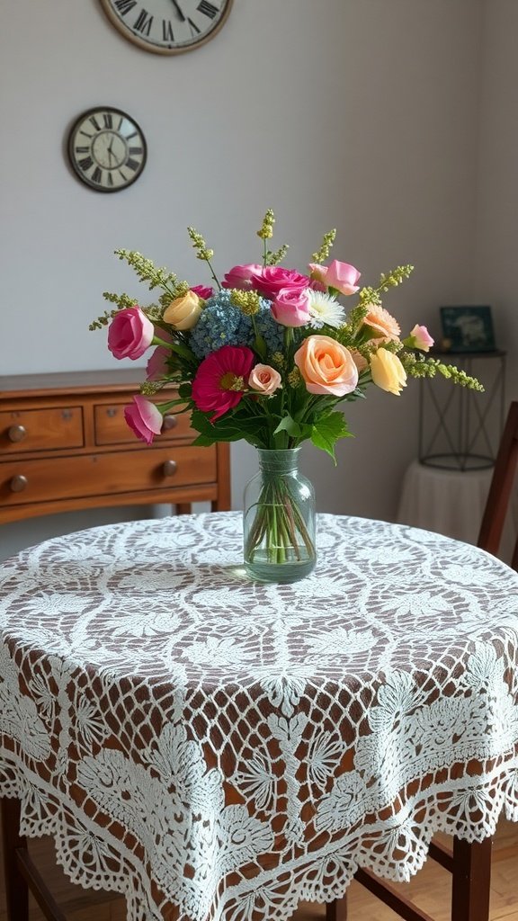 A round table draped with a lacy floral crochet tablecloth, featuring a vase of colorful flowers in the center.